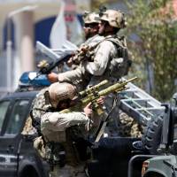 A member of the Afghan security forces aims his rifle during a firefight in Kabul on Monday. IS claims attack on Iraqi Embassy in Kabul