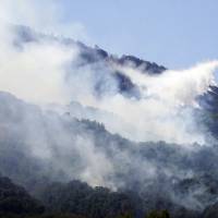 An anti-fire Canadair airplane flies over fires in the national park of mount Vesuvius near Naples, Italy, Monday. | CESARE ABBATE / ANSA / VIA AP