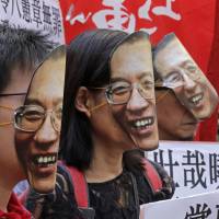 Protesters wear masks of jailed Chinese Nobel Peace Prize laureate Liu Xiaobo demand his release outside the Chinese liaison office in Hong Kong on June 27. China invites foreign experts to help treat ailing Nobel-winning dissident Liu