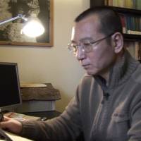 Liu Xiaobo looks at documents in his home in Beijing on Jan. 6, 2008. | AP