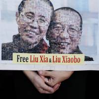 A portrait of Chinese Nobel Peace Prize winner Liu Xiaobo and his wife, Liu Xia, are displayed by protesters during a demonstration outside the Chinese liaison office in Hong Kong on Wednesday. Liu Xiaobo died from liver cancer at a Shenyang hospital on Thursday. After Chinese Nobel laureate Liu's death, focus now turns to fate of his widow