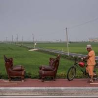 A man pushes a bicycle past two chairs Tuesday at the side of a road before the Demilitarized Zone (DMZ) separating the two Koreas (rear center) on the island of Ganghwa, west of Seoul. Large quake off North Korea coast 'not a nuclear test,' report says