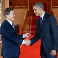 South Korean President Moon Jae-in shakes hands with former U.S. President Barack Obama at the Presidential Blue House in Seoul on Monday. | REUTERS