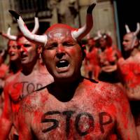 Animal rights protesters shout slogans after breaking mock banderillas containing red powder, which covered them during a demonstration for the abolition of bull runs and bullfights a day before the start of the famous running of the bulls San Fermin festival in Pamplona, northern Spain, Wednesday. | REUTERS