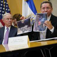 U.S. Attorney General Jeff Sessions looks toward El Salvador Attorney General Douglas Melendez Ruiz, who is holding up photographs during their meeting in San Salvador Thursday. Sessions steps away from fray, flies to El Salvador to probe ways to stamp out MS-13 gang