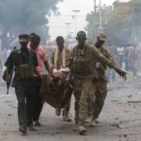 Somali soldiers evacuate a wounded man from the scene of an explosion in Maka al Mukaram road in Mogadishu Sunday. At least eight killed in al-Shabab attack on AU convoy in Somalia, five more in Mogadishu blast