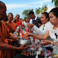 Buddhist monks wait receive alms from well-wishers during the birthday celebrations for Thai King Maha Vajiralongkorn in the southern Thai province of Narathiwat on Friday. 80% of Thai warning system crumbling 12 years after surprise tsunami
