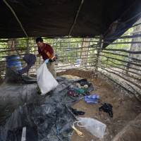 Forensic police collect items left at an abandoned migrant camp on Khao Kaew Mountain near the Thai-Malaysian border in Padang Besar, Songkhla province, southern Thailand, in 2015. According to investigators, smugglers held Rohingya Muslims fleeing persecution in Myanmar for ransom in jungle camps until relatives could pay for their release. | AP