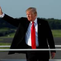 U.S. President Donald Trump waves Monday as he boards Air force One at Morristown municipal airport, New Jersey, en route back to Washington after a weekend at the Trump National Golf Club in Bedminster, New Jersey. Trump speaks with German, Italian leaders ahead of summit this week