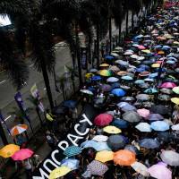 A banner extolling “Democracy” is carried during a protest march in Hong Kong on Sunday, the 20th anniversary of the city’s handover from British to Chinese rule. 'Schoolmaster' Xi leaves Hong Kong smarting