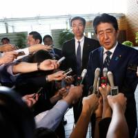 Shinzo Abe speaks to reporters as he arrives at the Prime Minister\'s Office on Monday in the wake of his Liberal Democratic Party\'s crushing defeat in the Tokyo Metropolitan Assembly election. | REUTERS