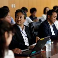 Motoyuki Yufu (center), deputy director-general of the Planning and Coordination Bureau at the Financial Services Agency, holds a meeting with other FSA staff, investors and influential bloggers at the agency in Tokyo on June 29. FSA turns to bloggers to shame dodgy, nonperforming funds