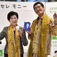 Tokyo Gov. Yuriko Koike and comedian Pikotaro hold energy-efficient LED lightbulbs at a Tokyo Metropolitan Government event Monday to promote a free exchange program aimed at accelerating the replacement of incandescent lights. | KYODO