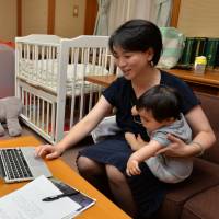Local lawmaker Misaki Hibi works while caring for her son in a day care room set up inside Nagoya City Hall by Democratic Party members of the municipal assembly. | CHUNICHI SHIMBUN