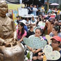 Protesters gather next to a statue symbolizing the \"comfort women\" in front of the Japanese Embassy in Seoul on Wednesday. | KYODO