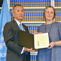 Hiroshi Minami, deputy permanent representative of Japan to the United Nations, displays on Tuesday Japan\'s instrument of acceptance of the U.N. Convention against Transnational Organized Crime at the United Nations in New York. | KYODO
