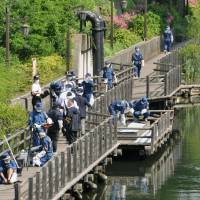 Police officers on Monday investigate a boardwalk along a river in Koto Ward, Tokyo, where a man in his 40s and his 9-year-old son vanished while fishing overnight Sunday. | KYODO