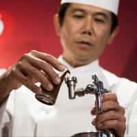 Yasumasa Takagi, owner and head chef of Le Patissier Takagi, pours liquid chocolate into an airbrush during a media preview of the Kit Kat Chocolatory Ginza store in Tokyo on Monday. From wasabi to raspberry, Japan's exotic Kit Kat varieties a sure win with tourists