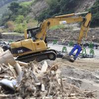 An excavator clears dirt in Asakura, Fukuoka Prefecture, on Tuesday as the prefecture shifts its focus to reconstruction. | KYODO