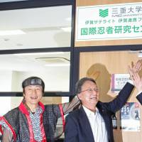 Iga Mayor Sakae Okamoto (left) and Mie University president Yoshihiro Komada (center) show off a sign for the international ninja research center in Iga, Mie Prefecture, on July 1. | KYODO