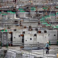 A construction worker walks through the site of the new National Stadium for the 2020 Olympics in May. Quake, tsunami, volcano risks stalk Olympic organizers