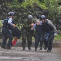 Ground Self-Defense Force personnel help a resident who had been isolated following heavy flooding in Asakura, Fukuoka Prefecture, on Friday. | AFP-JIJI