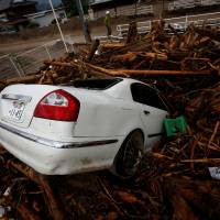 Debris and a car which were swept away by heavy rain are seen in Asakura, Fukuoka Prefecture, on Saturday. | REUTERS