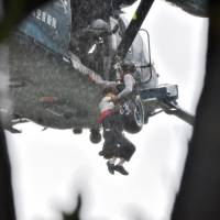 The 4th Division of the Ground Self-Defense Forces help a local resident evacuate after heavy flooding in Asakura, Fukuoka Prefecture, on Friday. | AFP-JIJI PHOTO / 4th DIVISION OF JAPAN GROUND SELF-DEFENSE FORCE