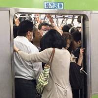 Passengers squeeze into a morning rush-hour train on the Yamanote Line, one of the busiest lines in the heart of the capital, at JR Tokyo Station on June 28. | YOSHIAKI MIURA