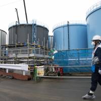 An employee walks past storage tanks for contaminated water at the tsunami-crippled Fukushima No. 1 nuclear power plant of the Tokyo Electric Power Co. in Okuma, Fukushima Prefecture, in February. Tepco needs to release the water — which contains radioactive tritium that is not removable but considered not harmful in small amounts — into the Pacific Ocean, Chairman Takashi Kawamura said. Fukushima's tritiated water to be dumped into sea, Tepco chief says