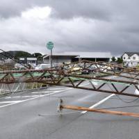A metal structure blocks a road in Kumamoto Prefecture after being knocked down by strong winds associated with Typhoon Nanmadol on Tuesday morning. The typhoon, the third of the season, made landfall in Nagasaki Prefecture. | KYODO