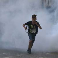 A Palestinian boy runs for cover from tear gas on Sunday during clashes between demonstrators and Israeli security forces at the Qalandiya checkpoint, between Ramallah and Jerusalem, in the occupied West Bank. The violent protests were triggered by new Israeli security measures implemented at Al-Aqsa mosque plaza, also know as the Temple Mount, in Jerusalem. How a 1929 dispute frames the Temple Mount conflict