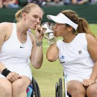 Yui Kamiji (right) and Jordanne Whiley kiss the trophy after winning their fourth consecutive women\'s wheelchair title at Wimbledon on Sunday. | KYODO