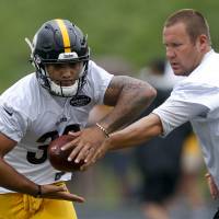 Pittsburgh Steelers QB Ben Roethlisberger hands off to running back James Conner at training camp on Friday. Big Ben may bow out after season