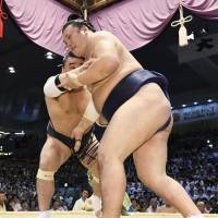 Yokozuna Harumafuji (left) grapples with Ikioi on Friday at the Nagoya Grand Sumo Tournament. Harumafuji improved to 4-2 with the victory. | KYODO
