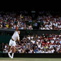 Roger Federer serves to Serbia’s Dusan Lajovic in their second-round match at Wimbledon on Thursday. Federer won 7-6 (7-0), 6-3, 6-2. Federer, Djokovic win in three sets
