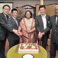 Madagascar Charge d\'Affaires Rosette Rasoamanarivo (center) takes part in a cake-cutting ceremony with (from left) JICA Executive Vice President Kazuhiko Koshikawa; Takumi Ihara, parliamentary vice-minister of the economy, trade and industry; Lower House member Yasutoshi Nishimura; and Angola Ambassador Joao Miguel Vahekeni to celebrate the 57th anniversary of the independence of Madagascar and the 55th anniversary of diplomatic relations between Madagascar and Japan at the embassy in Tokyo on June 26. | YOSHIAKI MIURA