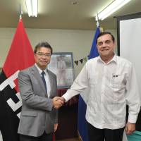 Nicaraguan Ambassador Saul Arana Castellon (right) greets Tatsuya Yoshioka, founder and director of nongovernment organization Peace Boat, at a conference in Tokyo titled Nicaragua: Path to Peace on the 38th anniversary of the Nicaraguan Revolution on July 19. | YOSHIAKI MIURA