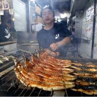 Grilled eel on skewers is prepared at a restaurant in Osaka on Tuesday &#8212; the Day of the Ox &#8212; when people in Japan traditionally eat the delicacy to help them endure the summer heat. | KYODO