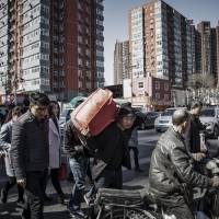People cross a street in Beijing. China is thinking about how to avoid what happened in Japan after its epic bust in the 1990s and the decades of stagnation that followed. China's fear of becoming Japan fueling crackdown on leverage, corporate buying sprees
