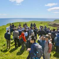 Japanese government officials and private-sector experts inspect a site scheduled for a hot springs resort development on Russian-held, Japan-claimed Kunashiri Island on June 28 during a visit to assess potential joint economic activities. | KYODO