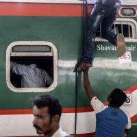 A man climbs onto the roof of a train at a station in Bangladesh. Kawasaki Heavy Industries Ltd. and Mitsubishi Corp. have won a &#165;40 billion order to supply 144 train cars and maintenance depot equipment for Bangladesh\'s first rapid transit railway system. | BLOOMBERG