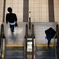 Pedestrians ride escalators in the Shibuya district of Tokyo. Rising labor costs, especially for part-time help, cast shadow on Japanese companies