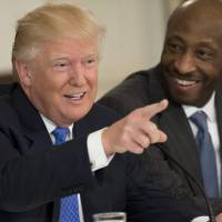 U.S. President Donald Trump speaks in February alongside Merck CEO Kenneth Frazier during a meeting with manufacturing CEOs in the State Dining Room at the White House in Washington. President Donald Trump lambasted Merck\'s CEO on Monday after the African-American pharmaceutical executive resigned from a White House advisory council, citing Trump\'s controversial response to a violent white supremacist rally. | AFP-JIJI