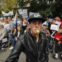 Disabled people, some in wheelchairs, take part in a protest outside the Labor Ministry in Bucharest Tuesday. Hundreds of disabled people joined the protest to express their anger at a government emergency decree that changes the current law and no longer obliges companies with more than 50 employees to hire a number of disabled people or use the services of a department that hires special needs personnel that could lead to 2,000 disabled people losing their jobs. Disabled people protest in Bucharest over decree dropping special needs hiring requirement