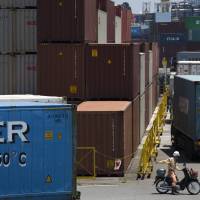 A worker sits on a scooter near a stack of shipping containers at a port in the city of Shizuoka. Japan’s current account surplus expanded in the January-June period to its highest level since 2007. Japan's current account surplus sets 10-year high in first half of 2017