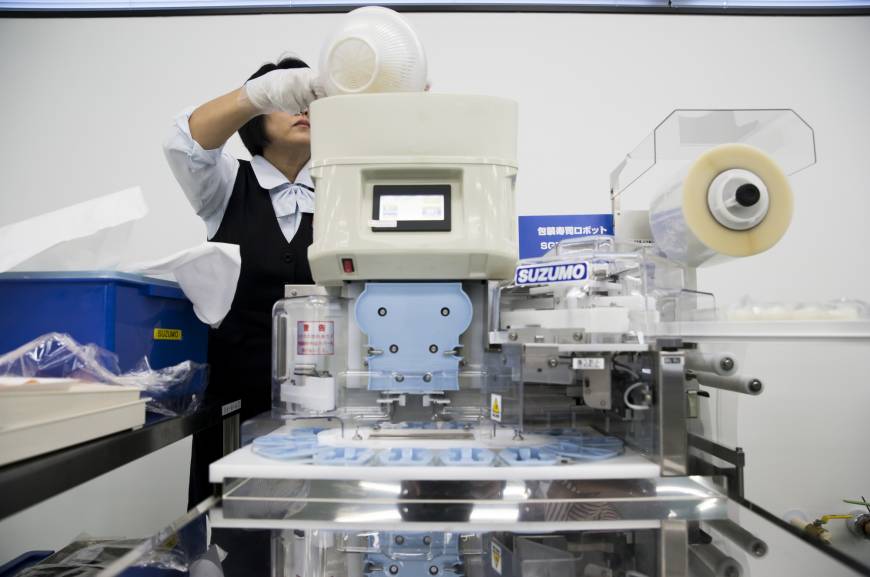 An employee puts a bowl of rice into a Suzumo Machinery Co. sushi machine during a demonstration.