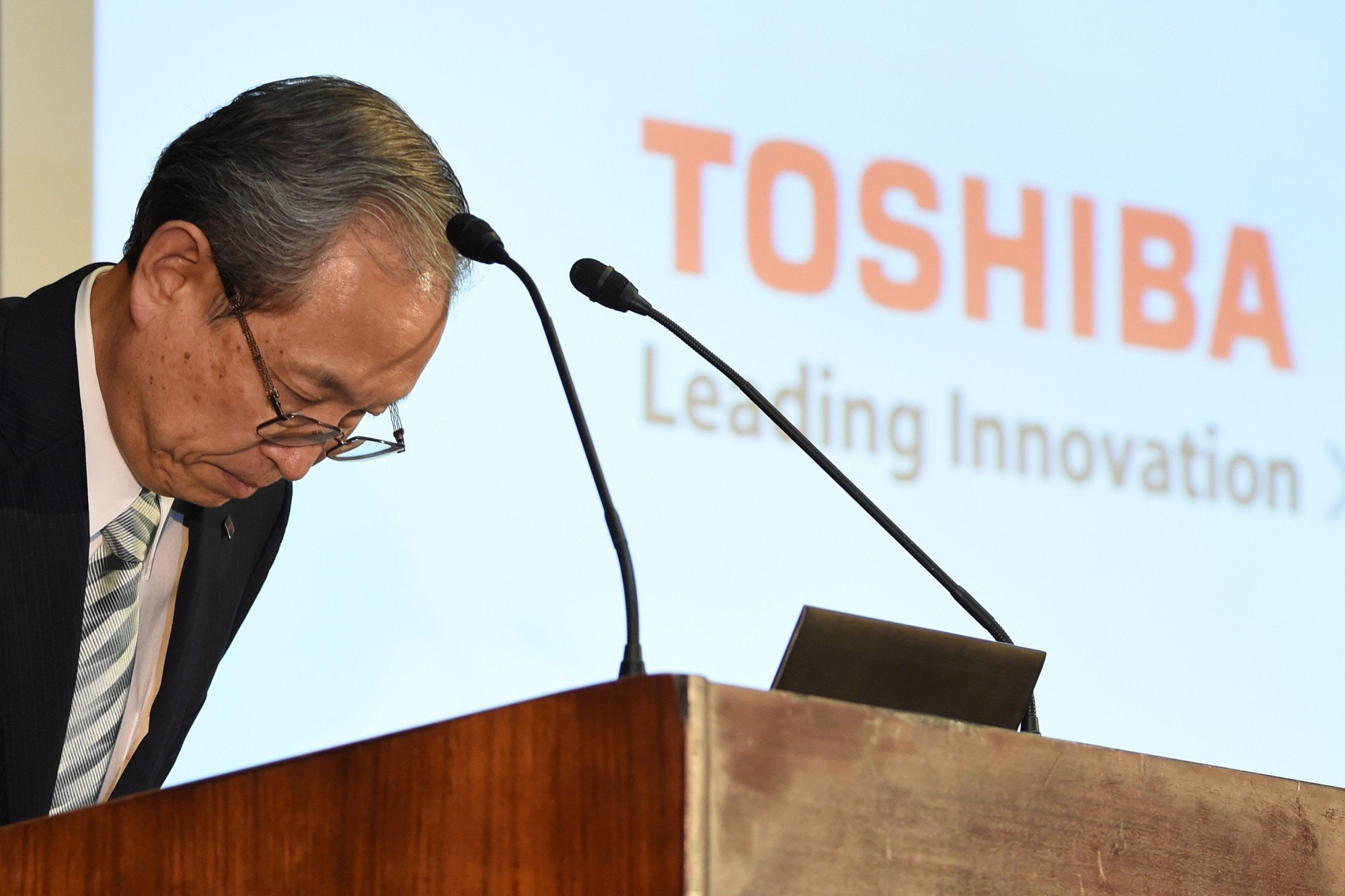 Toshiba President Satoshi Tsunakawa bows at a news conference at Toshiba headquarters in Tokyo on Thursday. | AFP-JIJI