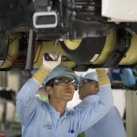 Toyota Motor Corp. employees work on an assembly line at its plant in Toyota, Aichi Prefecture. | BLOOMBERG
