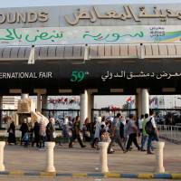 People walk at the Damascus International Fair in Damascus Sunday. Rocket fire kills six at entrance to Damascus trade fair that opened with great fanfare
